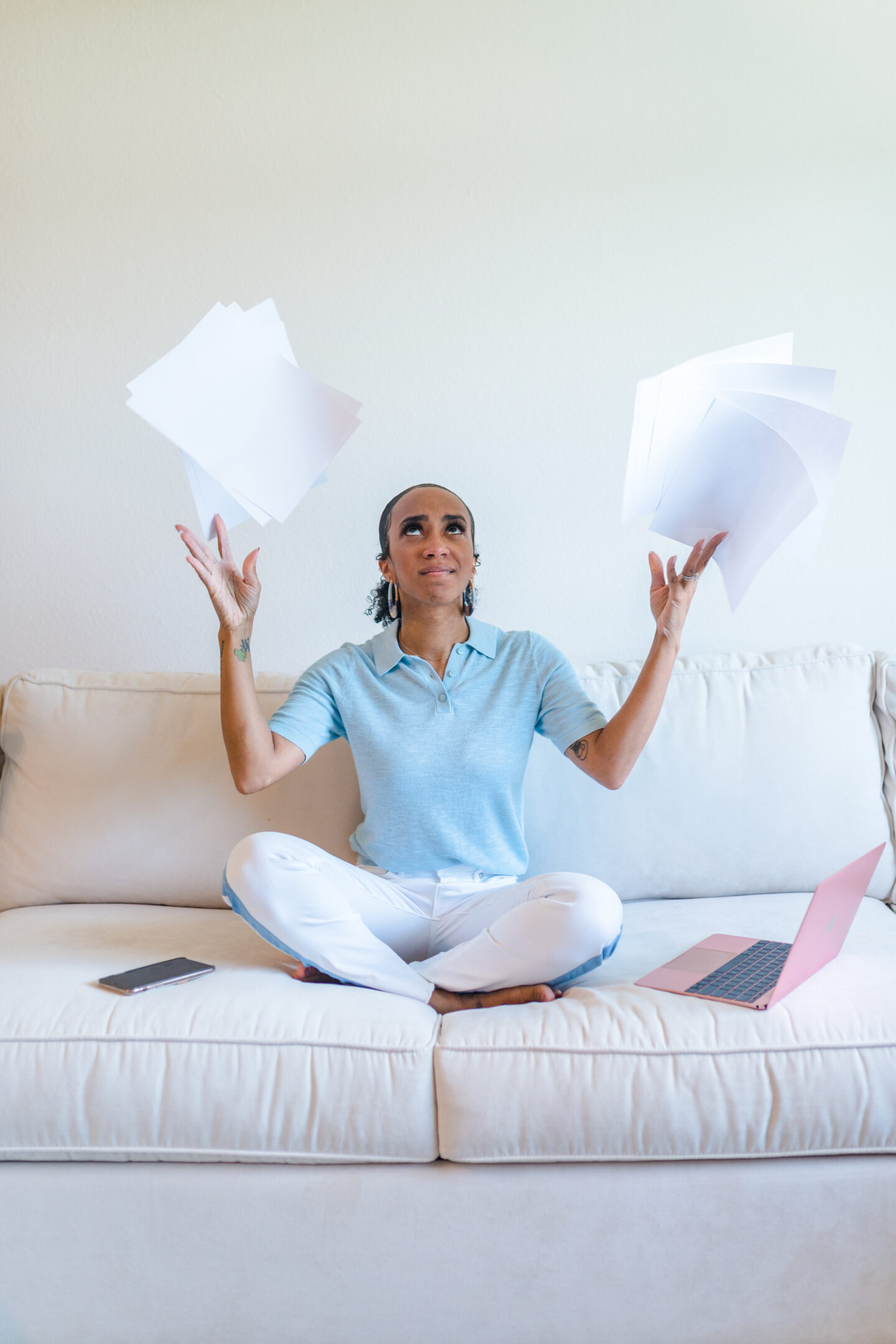 woman sitting on the couch and throwing papers 