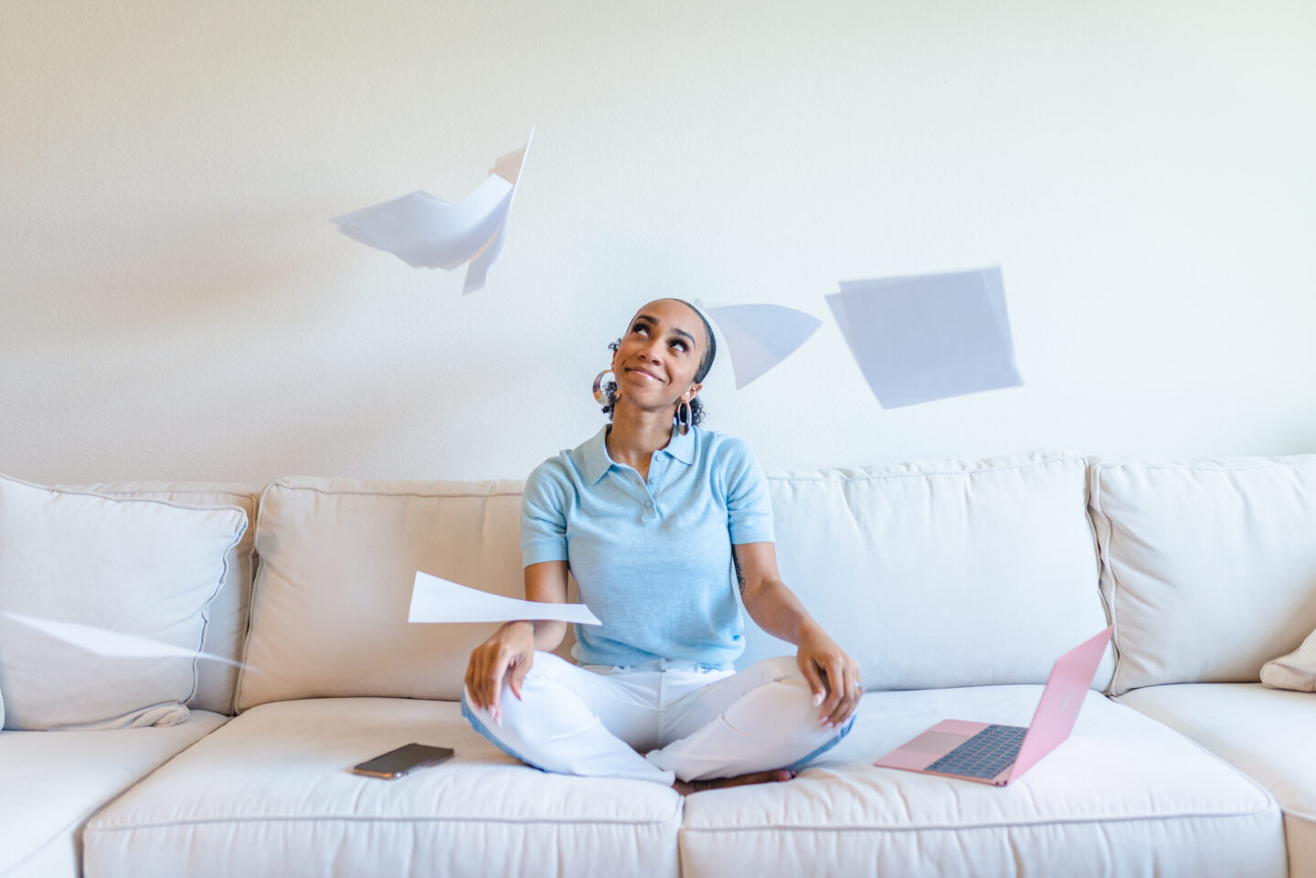 woman sitting on the couch and throwing papers and sharing Budgeting with YNAB 