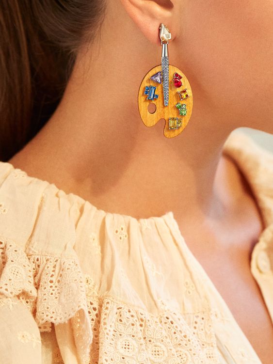 woman wearing painting themed earrings 